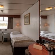 Twin cabin with two single beds, window view, wooden furniture, wall lamps, and mirror on the Switzerland ship's main deck.