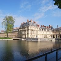 Das Schloss Fontainebleau spiegelt sich in einem ruhigen See und zeigt die prächtige französische Renaissance-Architektur mit vielen Schornsteinen.