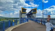 Woman viewing the modern Schiffshebewerk Niederfinow boat lift with yellow-topped towers and blue railings under a cloudy sky.