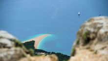 Luftaufnahme des Goldenen Horns auf Brač mit charakteristischer geschwungener Sandbank im türkisfarbenen Adriatischen Meer, Segelboote sichtbar.
