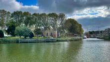 Ruhiges Hafenwasser in Medemblik mit historischem Schlossturm, grünen Bäumen und Segelbooten unter dramatischem Wolkenhimmel.