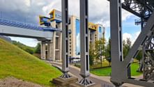 Massive concrete towers and steel framework of Schiffshebewerk Niederfinow boat lift with elevated waterway bridge and green landscape.