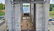 Massive concrete towers of the Niederfinow ship lift with the trough chamber visible between them. Visitors with bicycles stand at the base.