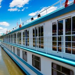 Weißes Flusskreuzfahrtschiff MS Switzerland mit türkisfarbenen Akzenten und großen Fenstern auf ruhigem Fluss unter blauem Himmel.