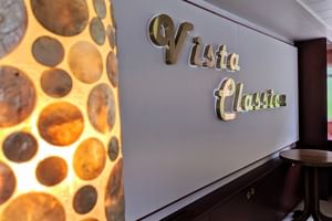 Innenwand mit metallischer 'Vista Classica' Beschriftung. Eine dekorative Lampe mit kreisförmigen Ausschnitten leuchtet warm auf der linken Seite.