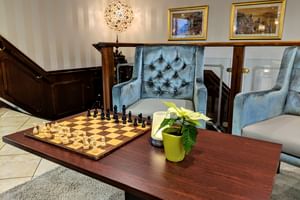 Eleganter Salon auf MS Classica mit blauen Samtsesseln, Schachspiel auf Holztisch, dekorativer Lampe und gerahmten Bildern an gestreiften Wänden.