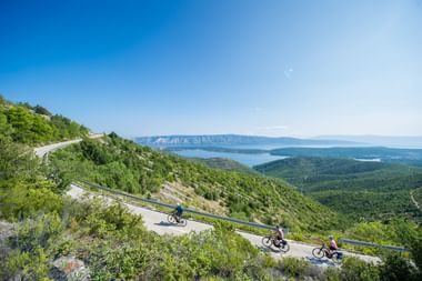 Ausblicke auf die kroatische Küste genießen Drei Radfahrer auf einer kurvigen Bergstraße in Norddalmatien mit Panoramablick auf die Insel Hvar und die Adria.