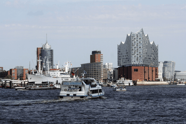 View of Hamburg Harbor with ferry boats on the Elbe River. The distinctive Elbphilharmonie concert hall dominates the skyline.
