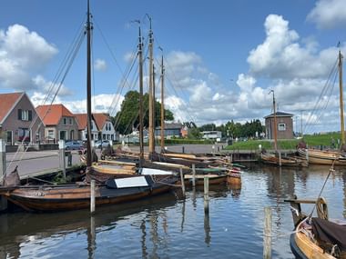Historischer Hafen in Elburg mit Segelbooten Traditionelle hölzerne Segelboote im Hafen von Elburg mit historischen niederländischen Häusern und einem Wasserturm im Hintergrund.