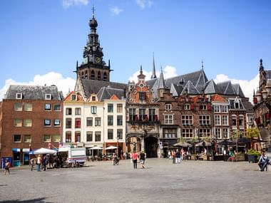 Nijmegen Grote Markt with historic buildings Historic Grote Markt square in Nijmegen with colorful traditional Dutch buildings, Gothic church tower, and people walking across the plaza.
