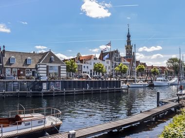 Hafen von Veere mit vertäuten Booten, Holzstegen und historischen Gebäuden am Wasser. Ein markanter Kirchturm ragt über die Stadt.