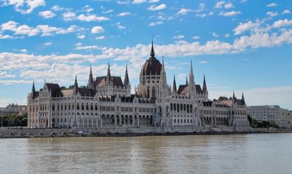 Das ungarische Parlamentsgebäude in Budapest von der anderen Seite der Donau aus gesehen, mit neugotischer Architektur und zentraler Kuppel.