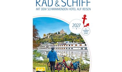 Katalogcover zeigt Radfahrer mit rotem Fahrrad am Fluss, Flusskreuzfahrtschiff und Burg auf Hügel im Hintergrund. Titel 'RAD & SCHIFF 2027'.