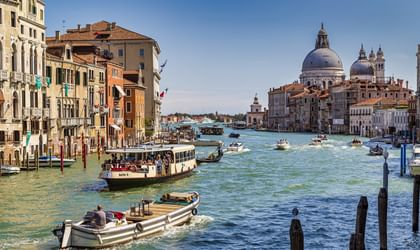Venedigs Canale Grande mit Booten und Vaporetto, historischen Palästen am Ufer und der Basilika Santa Maria della Salute mit ihren Kuppeln.