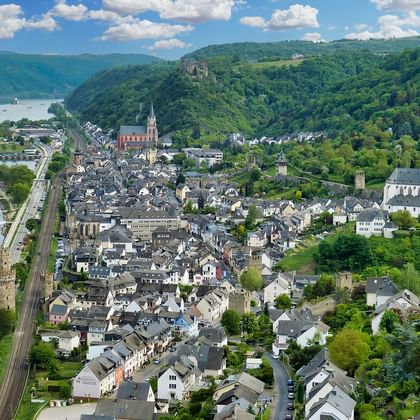 Aerial view of Oberwesel, a historic German town along the Rhine River with medieval towers, church spires, and traditional buildings.
