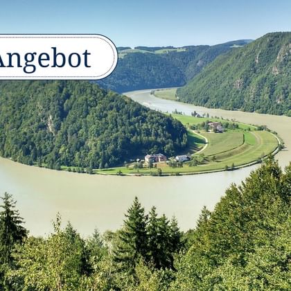 Luftaufnahme einer dramatischen Flussschleife der Donau, umgeben von dicht bewaldeten Hügeln und grünen Wiesen. Das Wort 'Angebot' ist sichtbar.