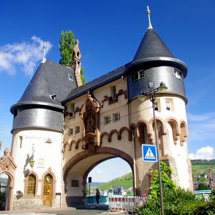 Mittelalterliches Torhaus mit zwei runden Türmen und Kegeldächern in Traben-Trarbach. Der Steinbau hat einen Torbogen und Verzierungen.