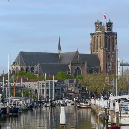 Dordrecht harbor with historic church tower Marina in Dordrecht with sailboats and yachts moored along the waterfront. Historic church with tall brick tower dominates the skyline.