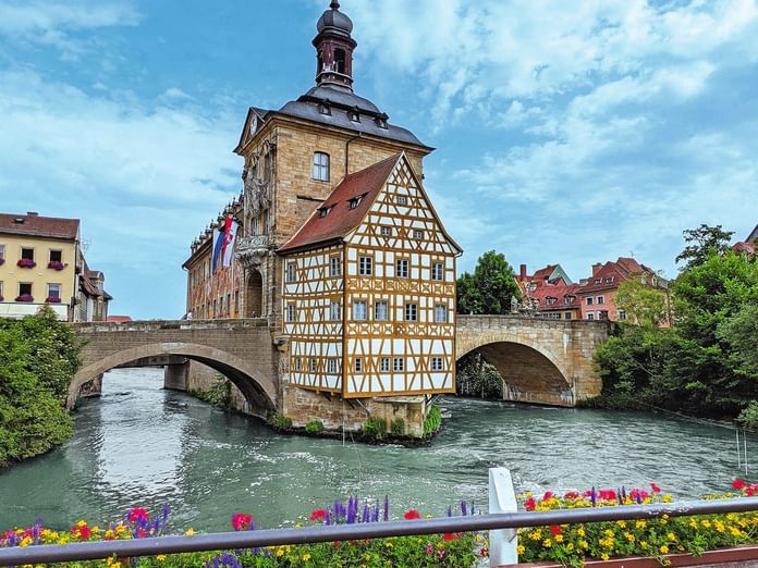Bambergs berühmtes Altes Rathaus mit Fachwerkfassade auf einer Brücke über die Regnitz, umgeben von bunten historischen Gebäuden.