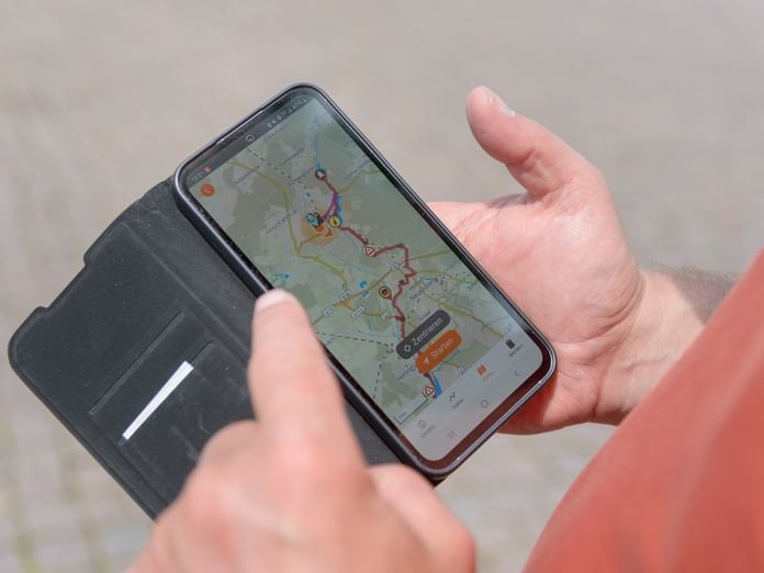 Hände halten Smartphone mit digitaler Karte und Routeninformationen, alle Reiseinfos immer dabei.