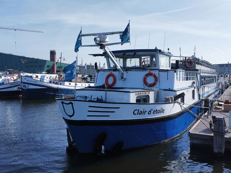 MS Clair d'Étoile im Hafen vertäut Weiß-blaues Passagierboot MS Clair d'Étoile am Steg vertäut mit orangen Rettungsringen und blauen Flaggen. Andere Boote im Hafen sichtbar.